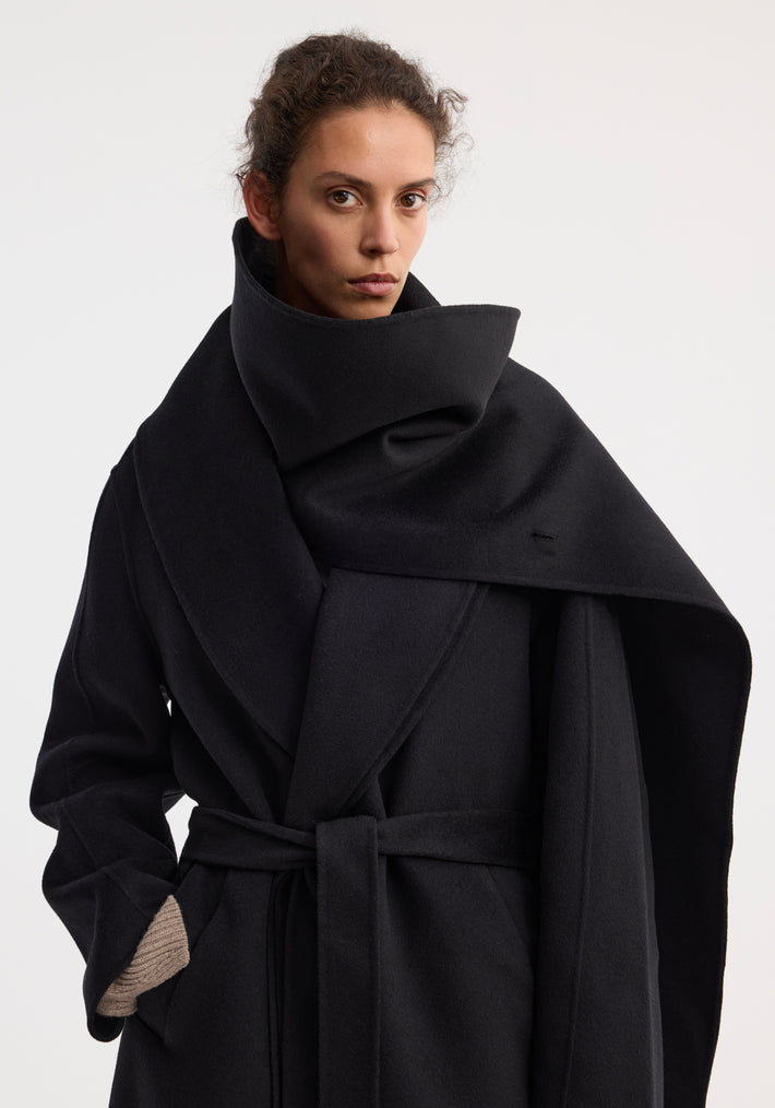 Young woman models the Signature double-faced scarf coat with belt, featuring a wrap-style, oversized collar, side pockets, and a full-length wool silhouette.