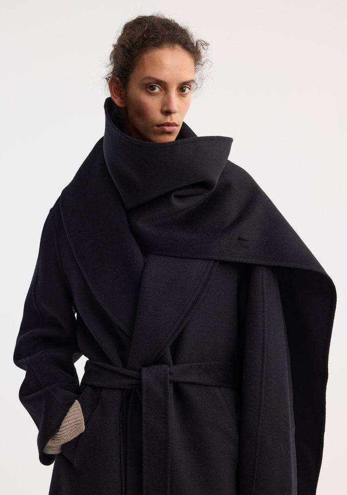 Model wearing Signature double-faced scarf coat with belt; features a sculptural shawl collar, long silhouette, side pockets, and wrap belt, crafted from 100% wool.