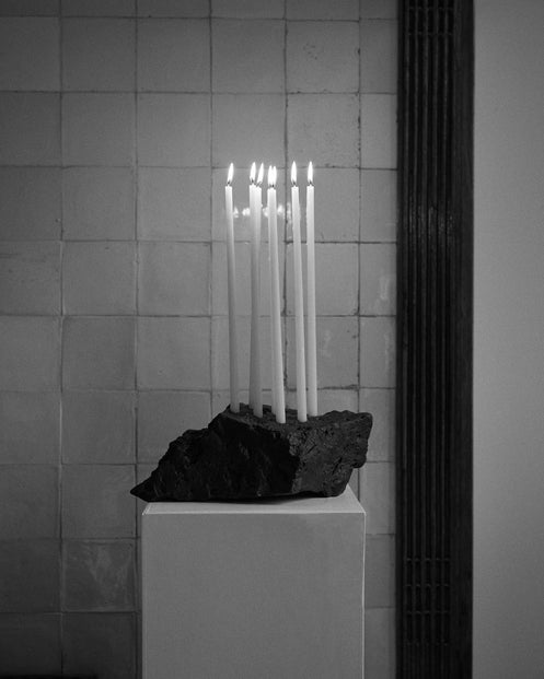 Sculptural Stone Candle Holder on a pedestal with seven lit taper candles, handcrafted from leftover lava stone by Dutch artist Louis Crombag.