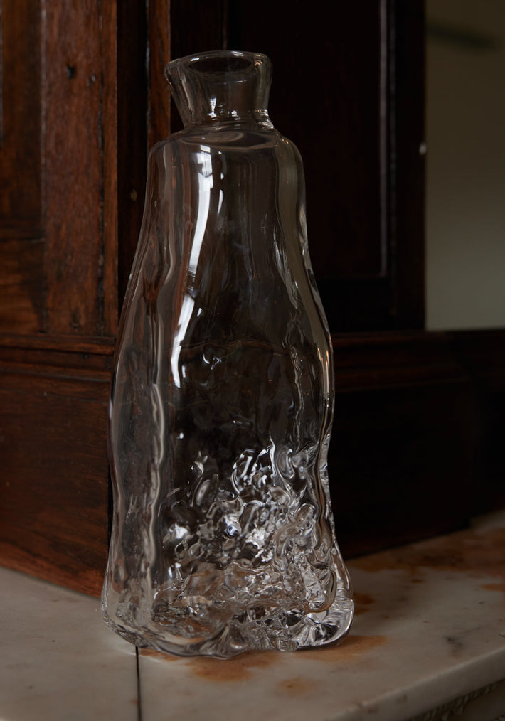 Blown vase | Glass: A clear, hand-blown glass vase with an organic, wavy silhouette and textured base, crafted by Szkło Studio, displayed on a stone ledge.