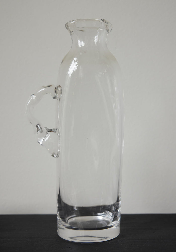 Large water carafe | Glass: A tall, hand-blown clear glass carafe with a stylized handle, showcasing unique craftsmanship by Szkło Studio.