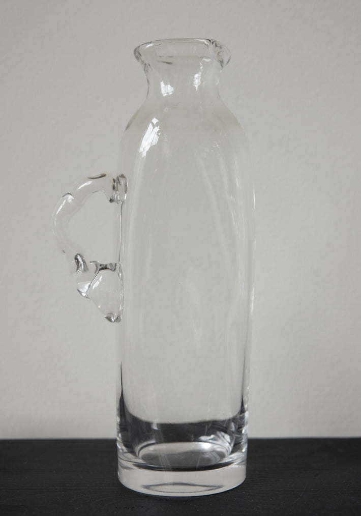 Large water carafe | Glass: A tall, hand-blown clear glass carafe with a stylized handle, showcasing unique craftsmanship by Szkło Studio.