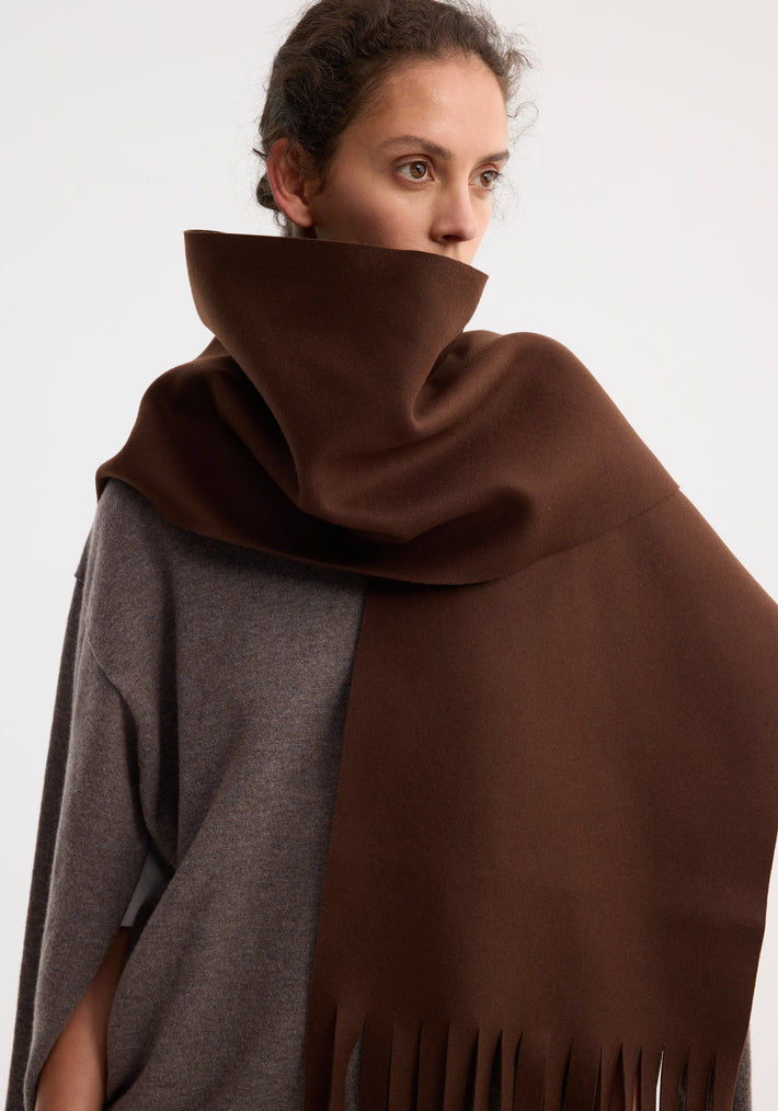 Person wearing a Wool scarf | pure chocolate, draped high around the neck with fringe, made from soft virgin wool by La Torre in Italy.