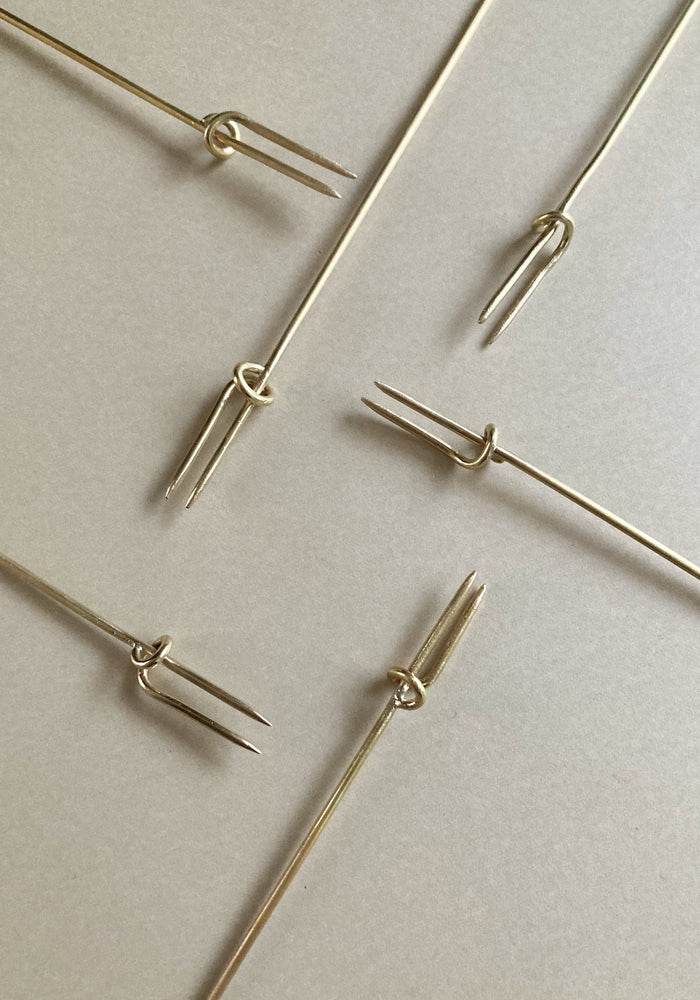 Vine Fork: Handcrafted, gold-tone, two-pronged picks inspired by nature, designed by Misae Nikkei in Kyoto, ideal for skewering appetizers like olives or cheese.