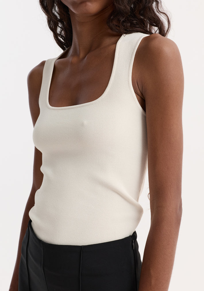 Bustier shaped knitted top in off white, featuring a square neckline and fitted design, worn with high-waisted black trousers. Crafted from viscose nylon blend.