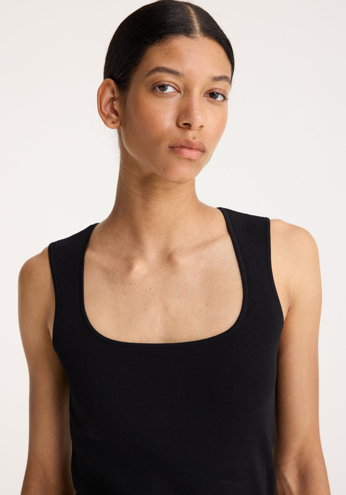 Young woman models the Bustier Shaped Knitted Top in black, showcasing its fitted, bustier-style neckline crafted from dense viscose-blend yarn.