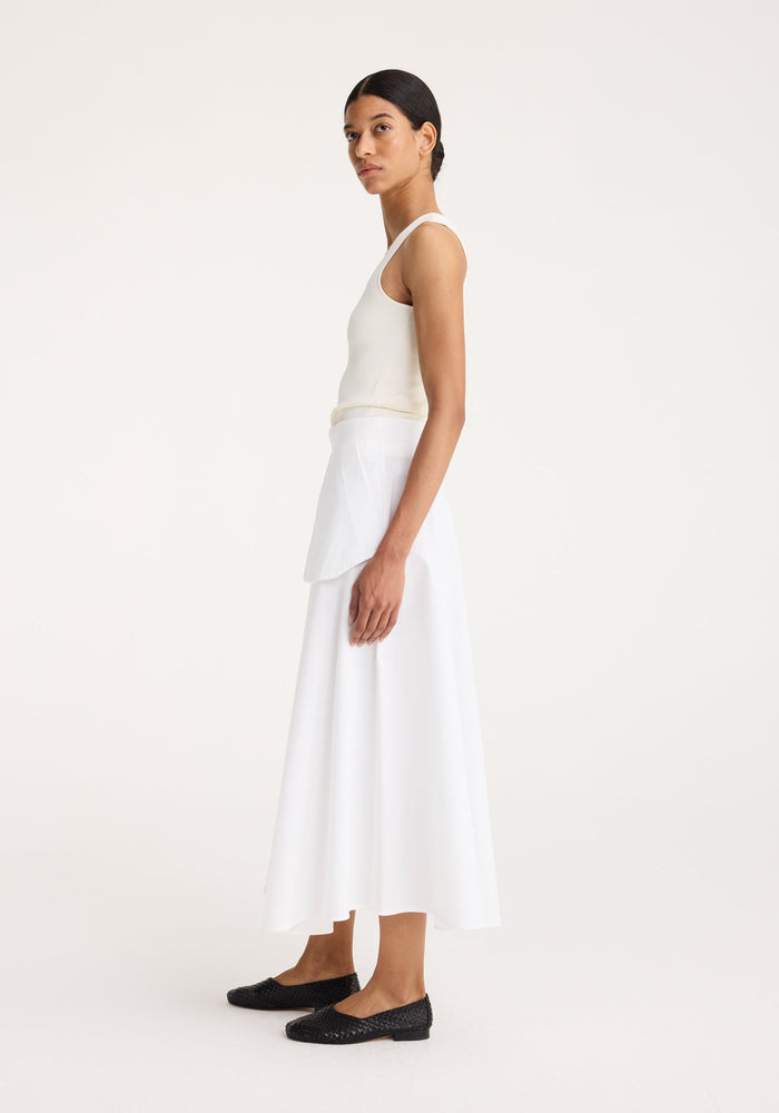 Bustier shaped knitted top in off white, worn by a model in profile, showcasing its fitted shape and bustier neckline, perfect for layering.