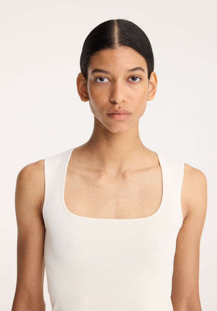 A young adult models the Bustier shaped knitted top in off white, featuring a square-neck design and ribbed texture, perfect for everyday wear.