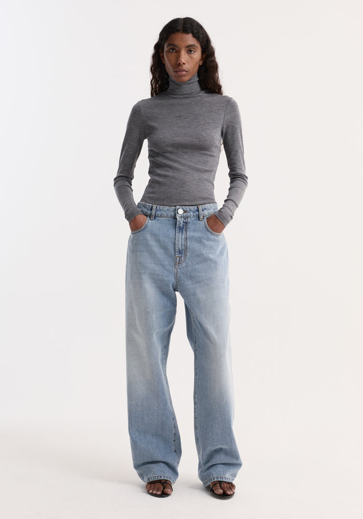 Model wears Fine merino turtleneck | mid grey melange, showcasing a fitted silhouette with long sleeves, paired with high-waisted jeans and dark sandals.