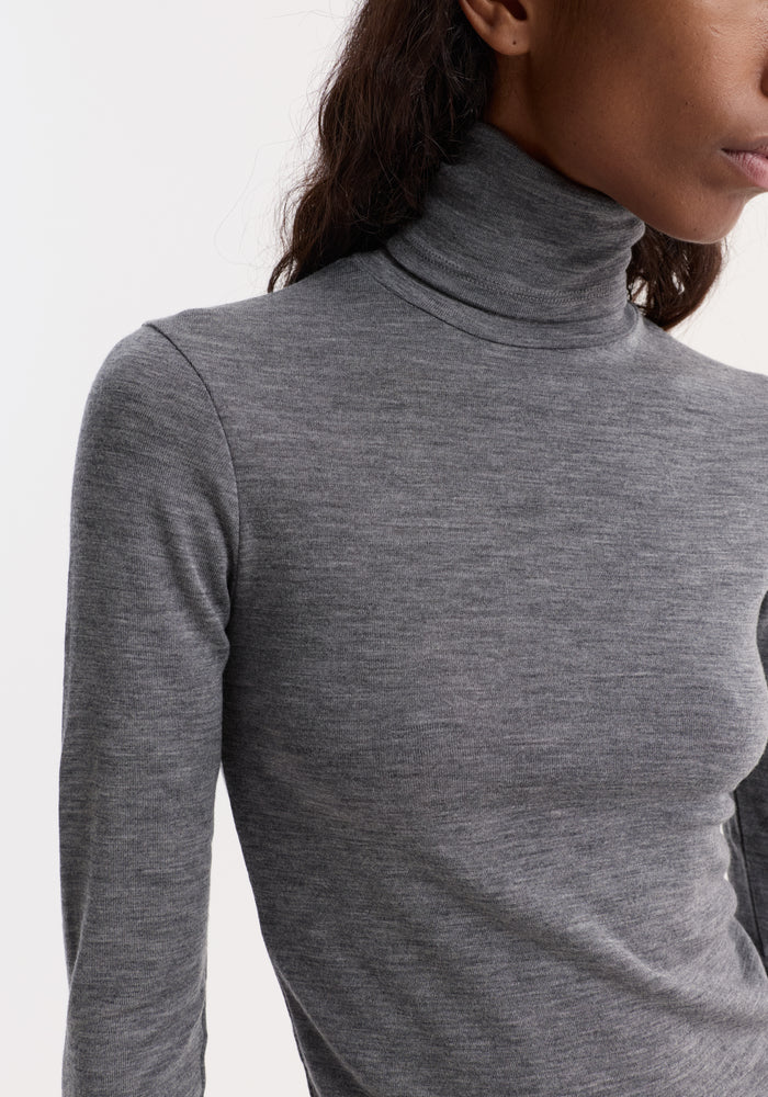 Model wearing the Fine merino turtleneck in mid grey melange, showcasing its fitted, long-sleeve design crafted from pure merino wool.