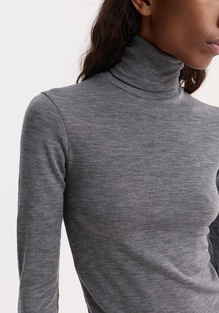 Model wearing the Fine merino turtleneck in mid grey melange, showcasing its fitted, long-sleeve design crafted from pure merino wool.