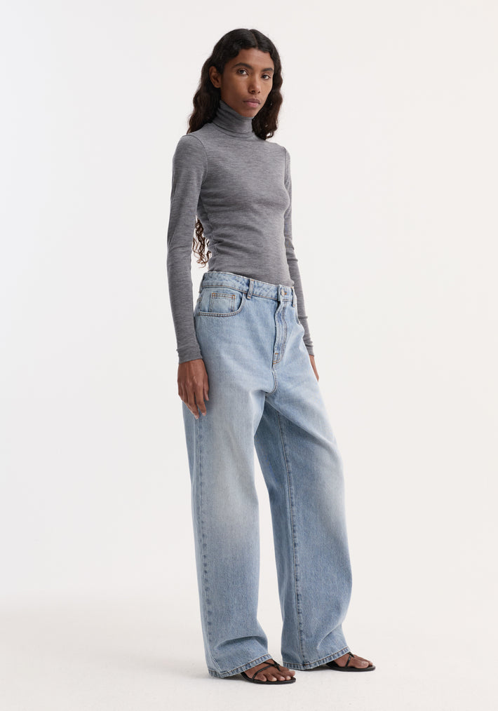 Model wearing Fine merino turtleneck in mid grey melange with high-waisted wide-leg jeans and black sandals, showcasing a minimalist, sleek silhouette.