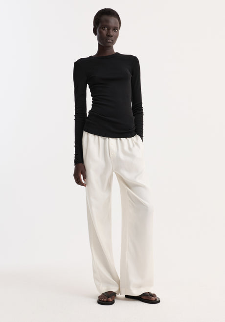 Model wearing Fine merino long sleeve in fitted silhouette, paired with high-waisted trousers and sandals, highlighting minimalist style.