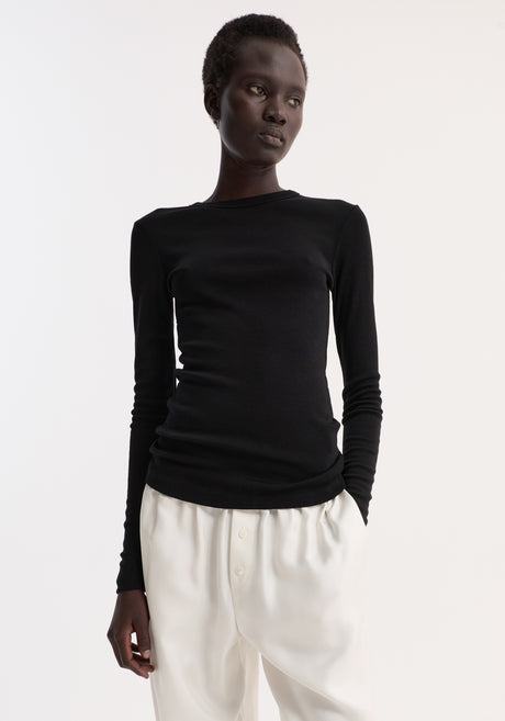 Model wearing Fine merino long sleeve in fitted silhouette, paired with high-waisted trousers and sandals, highlighting minimalist style.
