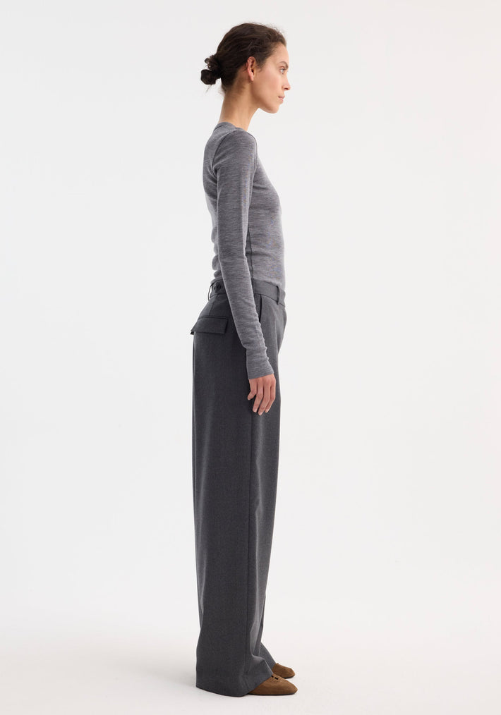 Fine merino long sleeve in mid grey melange, featuring a crew neck and fitted silhouette, worn by a model in high-waisted charcoal trousers and brown loafers.