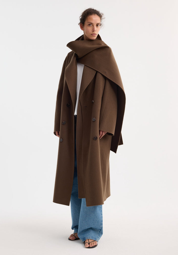 Signature double-faced scarf coat with a double-breasted design, wide shawl collar, and welted pockets. Made from 100% wool, featuring a distinctive double-layered scarf collar.