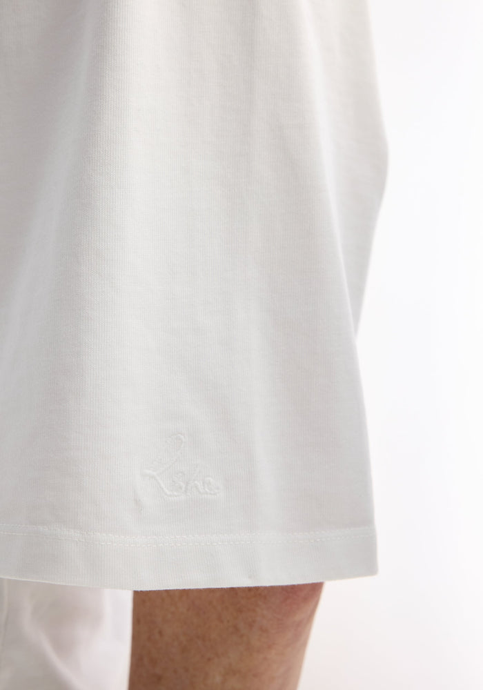Close-up of the Fitted logo T-shirt in optic white, showing the embroidered logo on the tapered sleeve hem, highlighting its crisp cotton texture.