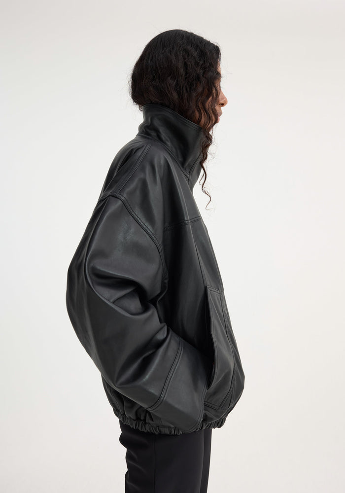 Reinvented leather jacket | black with a bomber silhouette, high stand-up collar, and roomy sleeves. Model wears size EU 40, showcasing its oversized fit.