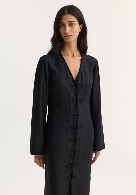 Mandarin silk dress | black: Model in a long, black silk dress with V-neck, pankou closures, long sleeves, and front slit, showcasing elegance and luxurious craftsmanship.