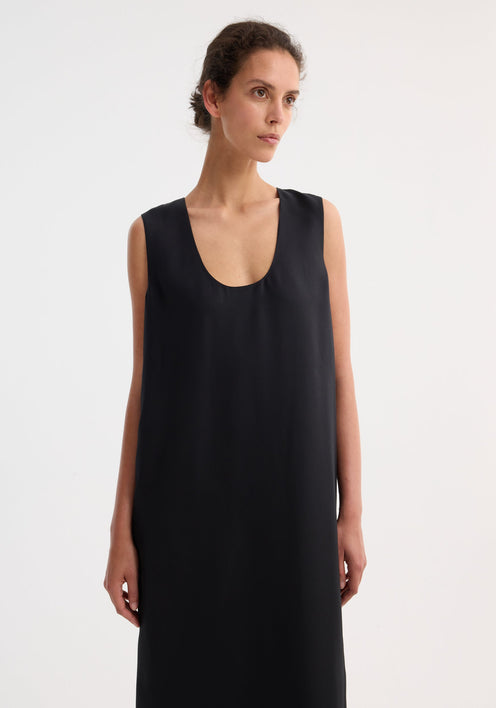 Model in a Scoop-neck silk dress | black, floor-length, sleeveless, with a relaxed silhouette and subtle front slit, paired with tan strappy sandals.