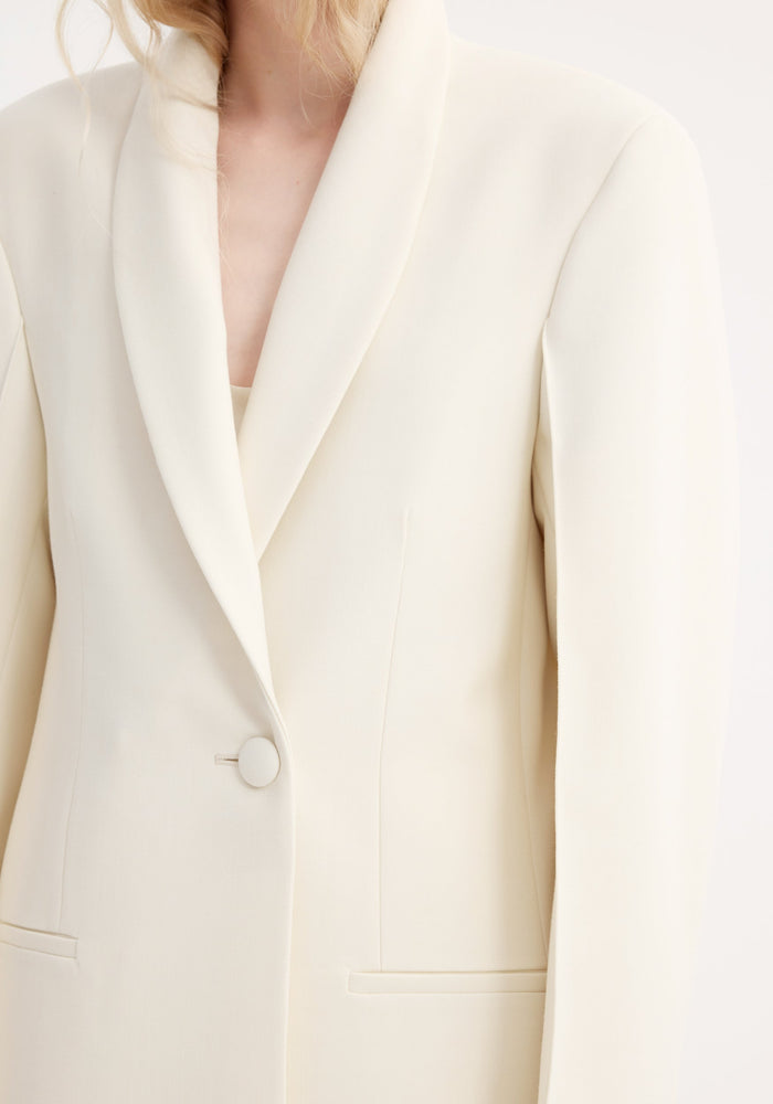 Close-up of a Signature opera coat in ivory, featuring a deep V-neck, shawl collar, single button closure, and narrow welt pockets, highlighting its elegant tailored design.