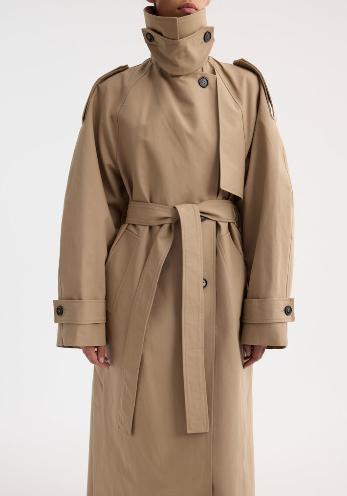 Person wearing Oversized classic trench | clay, featuring a high collar, epaulets, double-breasted front, wrap belt, and adjustable cuffs, highlighting its structured elegance.