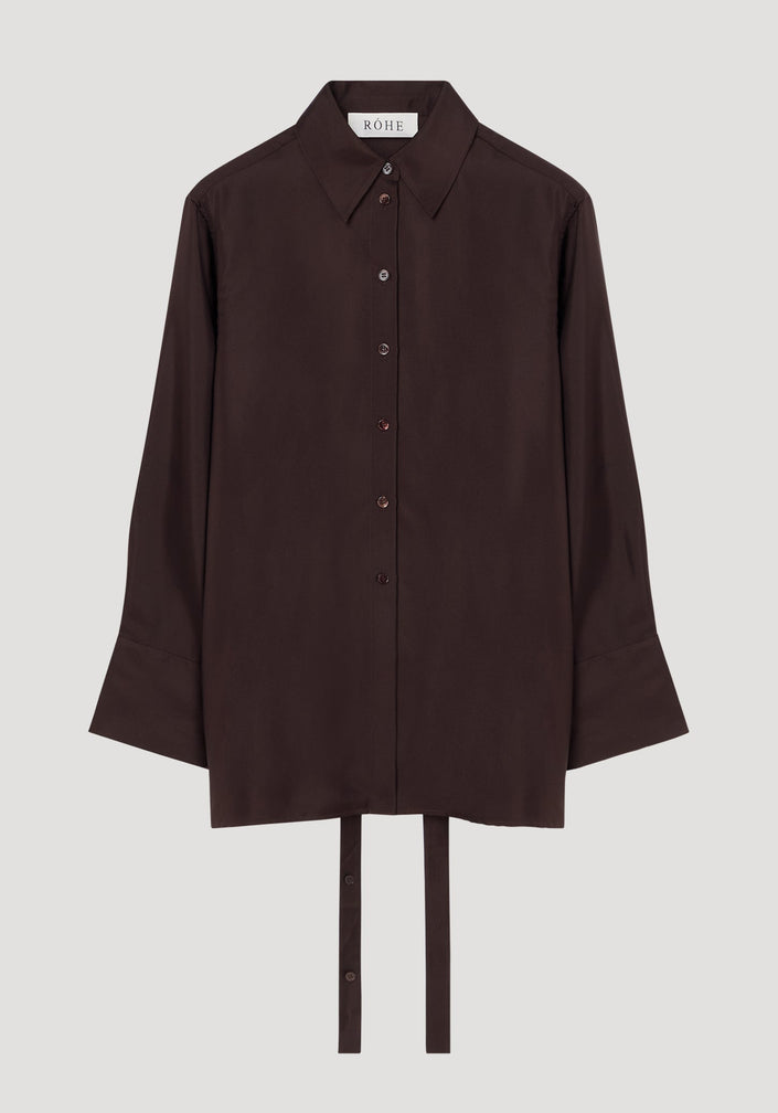 Deconstructed silk shirt in mahogany with an open back, pointed collar, and fabric ties for styling versatility, featuring a RÓHE label inside.