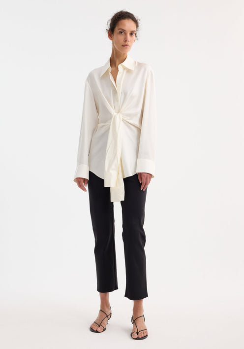 Silk knotted shirt | cream: Cream-colored, long-sleeve blouse with a pointed collar, featuring a unique twisted knot design at the waist for a draped effect.
