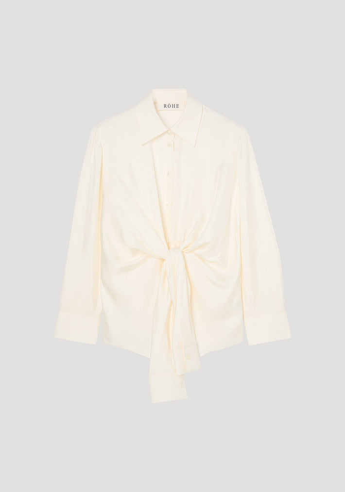 Silk knotted shirt | cream: Cream-colored, long-sleeve blouse with a pointed collar, featuring a unique twisted knot design at the waist for a draped effect.
