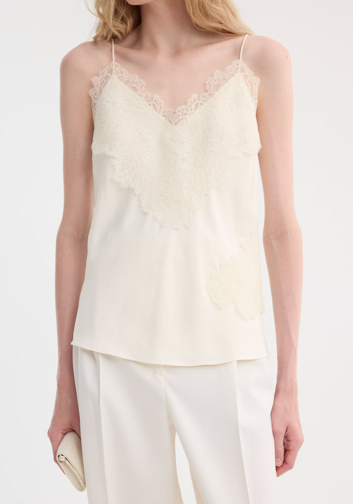 Lace camisole | cream: A chic ivory-cream top with lace trim, V-neckline, adjustable back straps, paired with matching trousers, held with a rolled clutch purse.