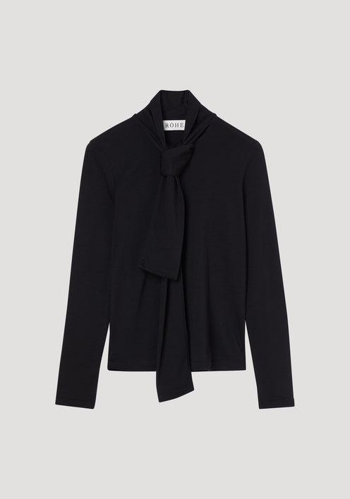 Merino scarf top | black: Women's fitted black long-sleeve turtleneck with an elegant scarf-style tie at the neckline, crafted from pure merino wool. RÖHE label visible.
