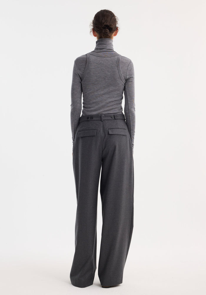 Double-layer wool top in mid grey melange worn by a model, showcasing a fitted turtleneck paired with high-waisted trousers, highlighting its tailored, monochromatic style.