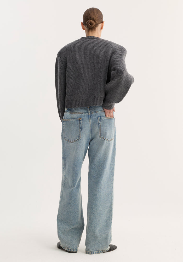 Model wearing Statement Shoulder Cardigan in mid grey melange, featuring an oversized fit and structured shoulders, paired with wide-leg jeans and slip-on shoes.