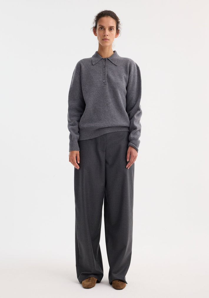 Woman in a minimalist outfit wears a Compact knitted polo in mid grey melange with a fold-down collar, paired with matching wide-leg trousers.