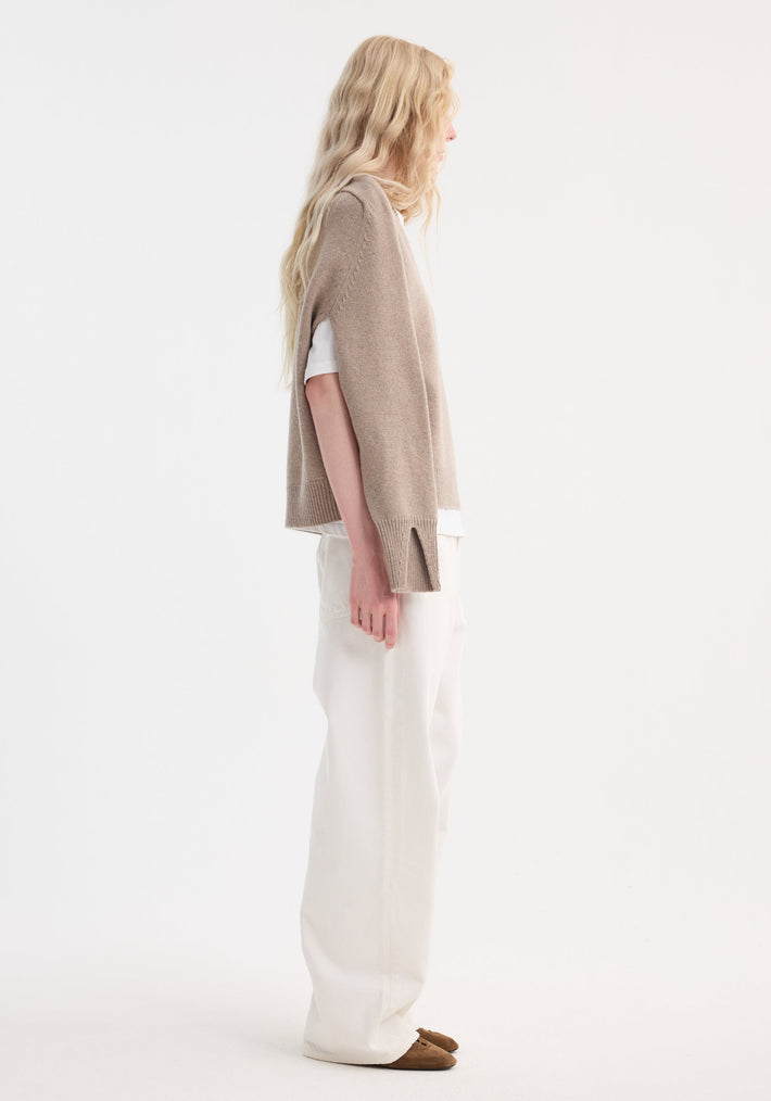 Model in a taupe melange Sleeve Wrap Jumper, showcasing its relaxed fit and wrap-sleeve design, layered over a white T-shirt with wide-leg trousers.