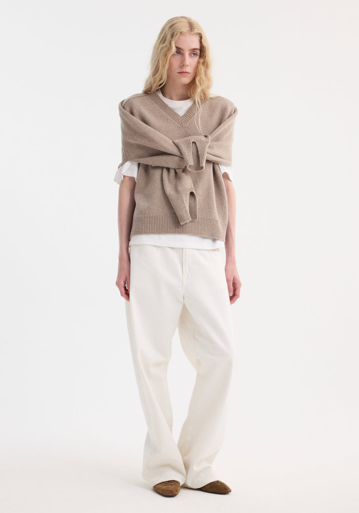 Model wearing Sleeve wrap jumper | taupe melange, showcasing its versatile wrap-sleeve design over a white tee, paired with loose-fit trousers and suede flats.