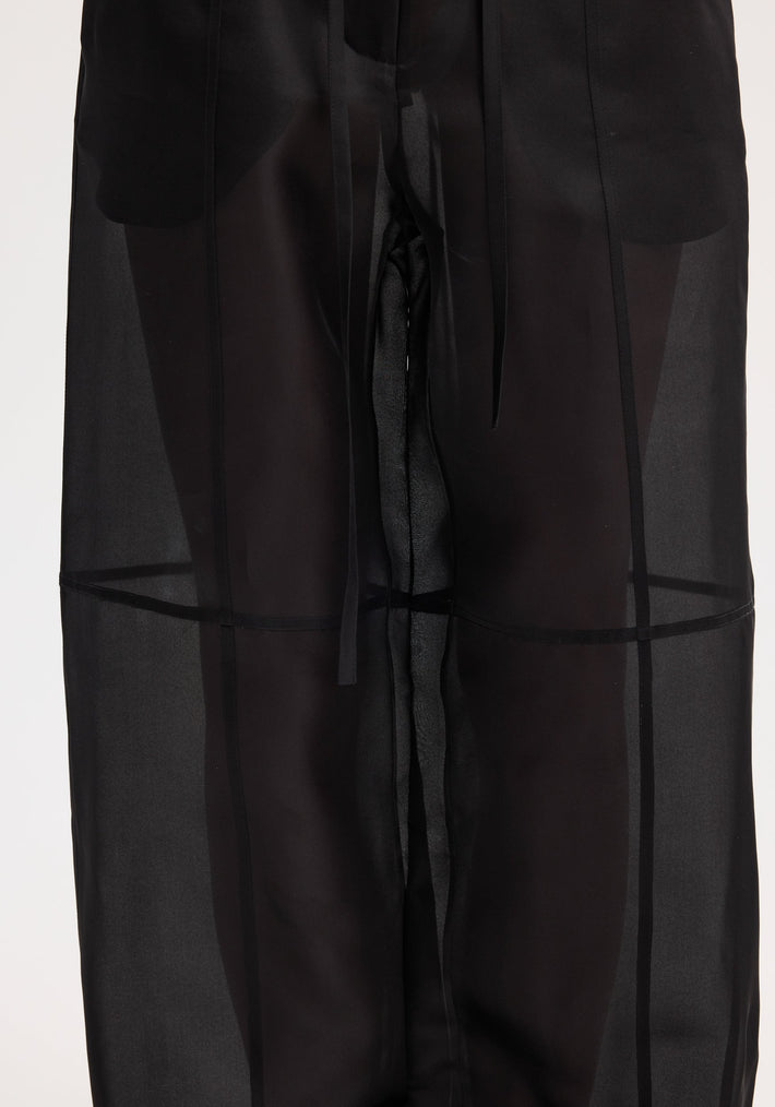 Organza silk parachute trousers in black, featuring sheer silk organza fabric, wide legs, and a drawstring waist, displaying elegance and fluidity.