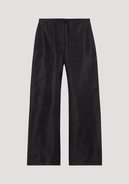Organza silk parachute trousers in black, featuring a wide-leg design and drawstring waist, crafted from sheer, flowing silk organza for elegant movement.