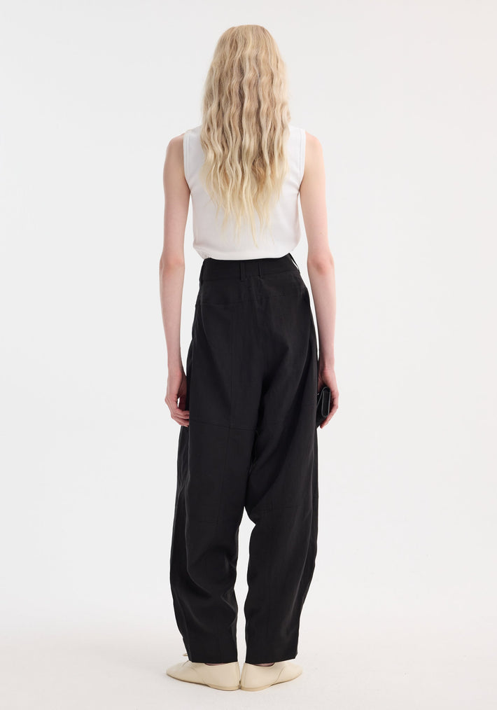 Back view of a person wearing Parachute trousers | black, showcasing high-waisted, wide-leg design in viscose-linen blend, paired with a white sleeveless top.