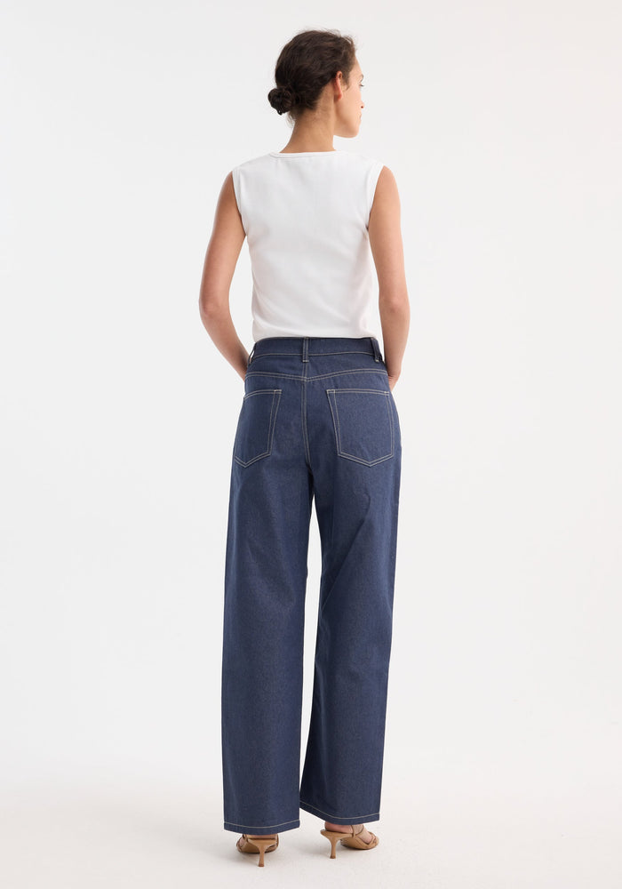 Signature baggy fit raw denim jeans with a wide leg and low-waist, worn by a model with a white sleeveless top and tan heeled sandals.