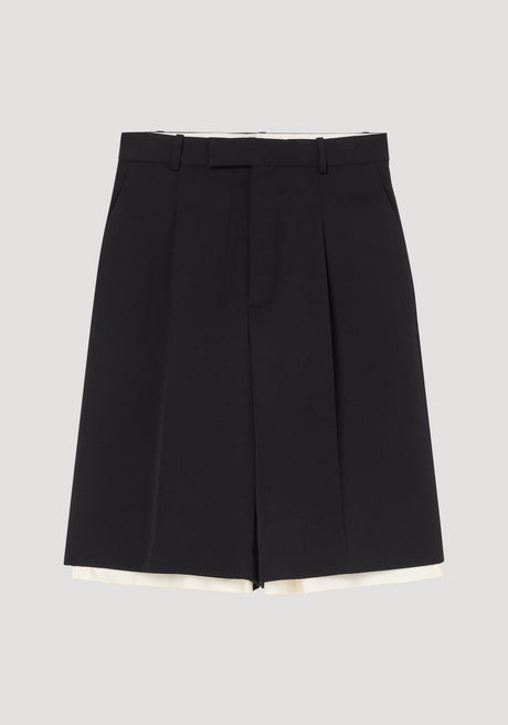 Contrast extended lining shorts in black, featuring high-waisted design, skirt-like front, belt loops, side pockets, and a subtle cream lining peeking beneath the hem.