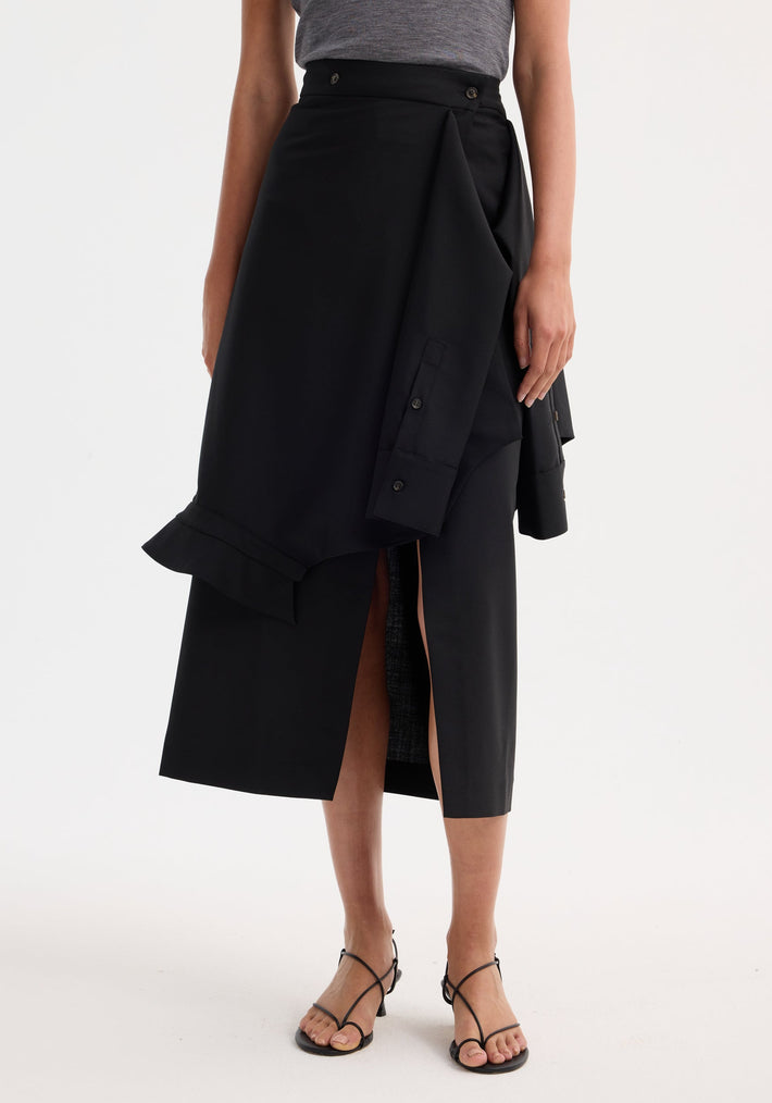 Shirt wrap skirt | black: Asymmetrical black midi skirt with buttoned waist, wrap overlay, center front slit, and deconstructed sleeve detail, worn with black strappy heels.