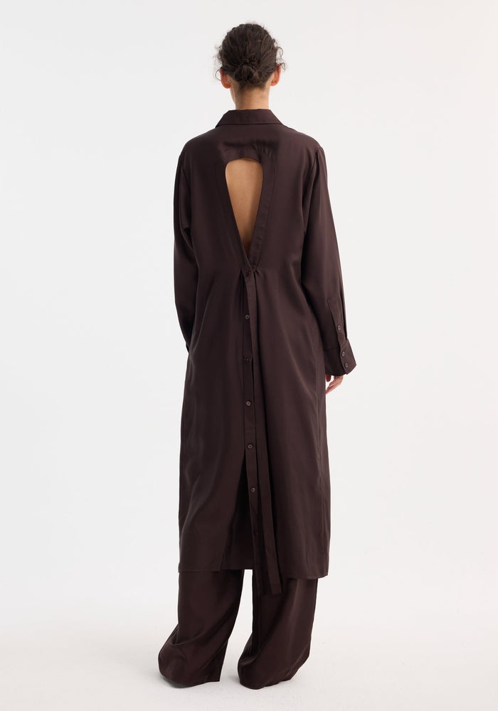 Silk open back wrap dress in mahogany, featuring a teardrop cutout and button-down back, paired with matching wide-leg trousers; styled with low bun.