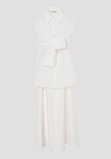 Poplin silk combined gilet-dress in optic white, featuring a deconstructed design with open armholes, buttoned wrap belt, and a fluid silk skirt.