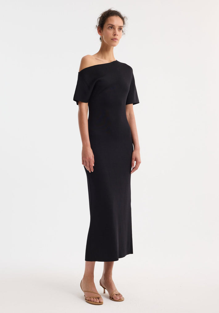 Asymmetrical knitted dress | black: Model in sculptural, off-shoulder midi dress showcasing elevated minimalism, quiet confidence, and intentional craftsmanship. A timeless design in high-end Italian fabrics.
