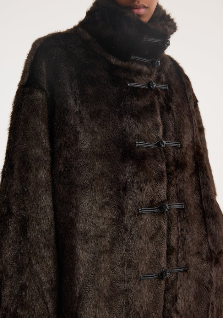 Mandarin faux fur coat in dark brown with high stand-up collar and horizontal toggle closures, showcasing a luxurious, oversized design.
