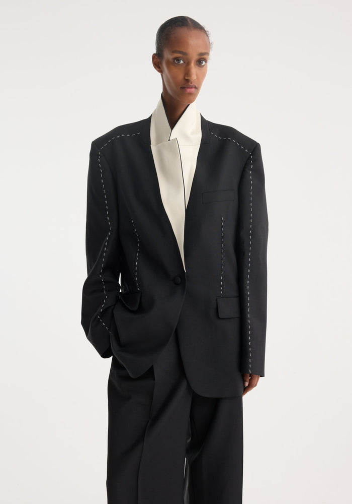 Person wearing Contrast detail blazer | black, featuring oversized fit, white contrast stitching on seams, and a striking white lapel underside, crafted from Italian wool-mohair blend.