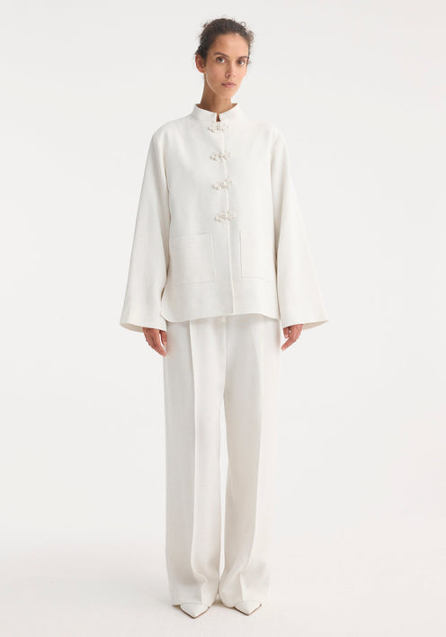 Mandarin jacket in winter white with pankou closures, square patch pockets, light silk-blend fabric, and wide sleeves; model is 179cm, wearing size EU 36.