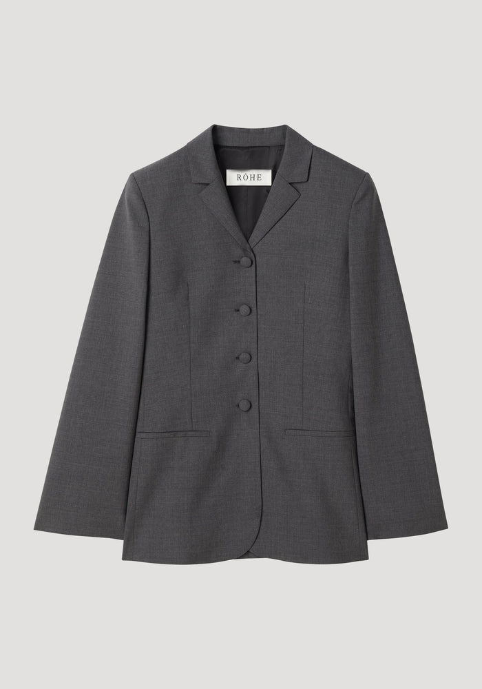 Fitted wool blazer in dark grey melange with notched lapel, fabric-covered buttons, and welt pockets, showcasing a tailored, figure-skimming silhouette. Label reads “RÓHE.”