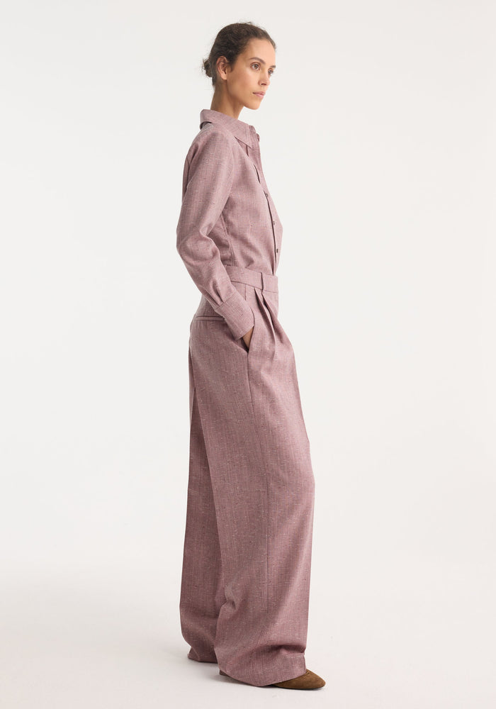 Model in profile wearing a Fitted tweed shirt | mauve melange, showcasing its tailored fit and sharp collar, paired with high-waisted trousers.